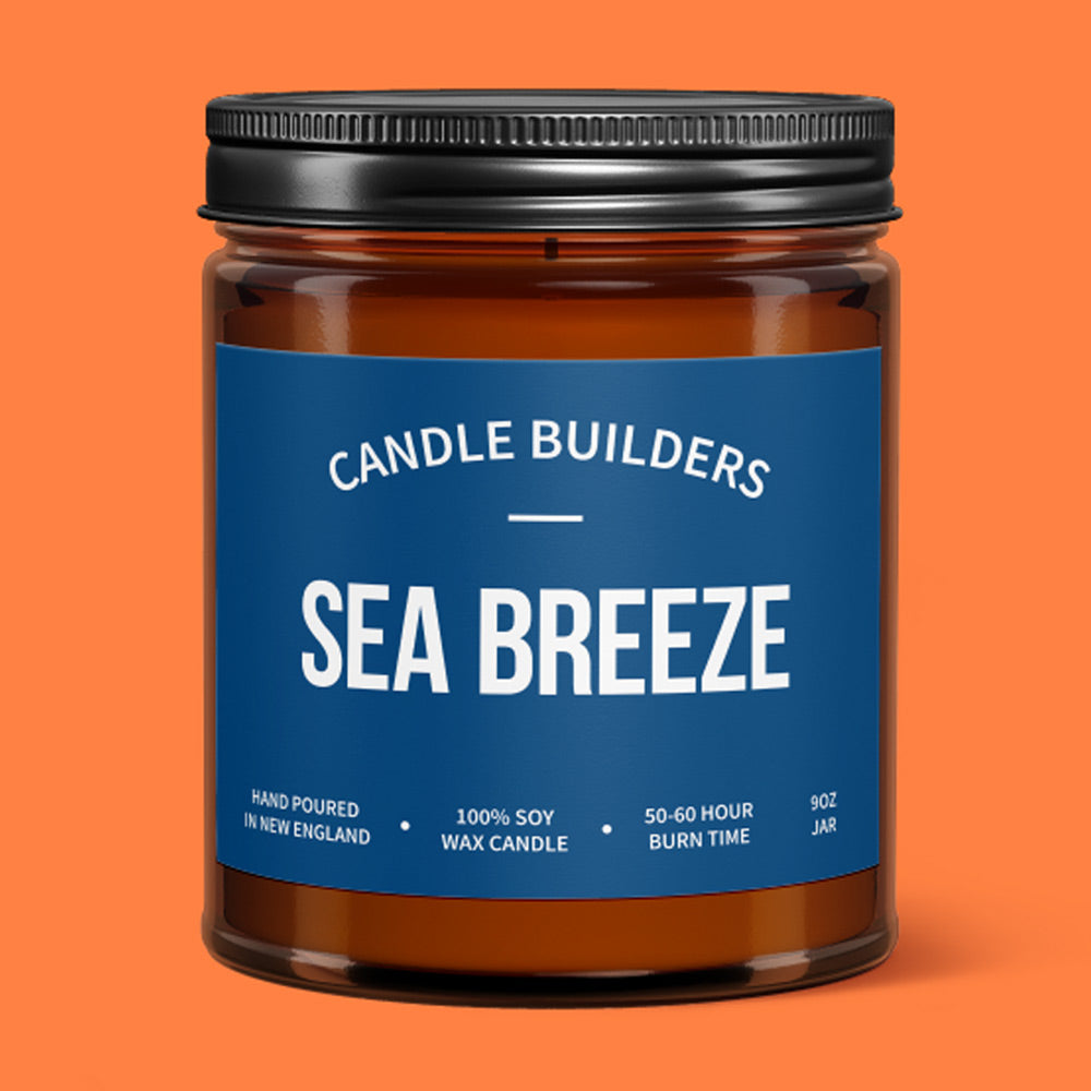 A photo showing a beautiful amber jar candle with a black lid. The label shows the scent is Sea Breeze
