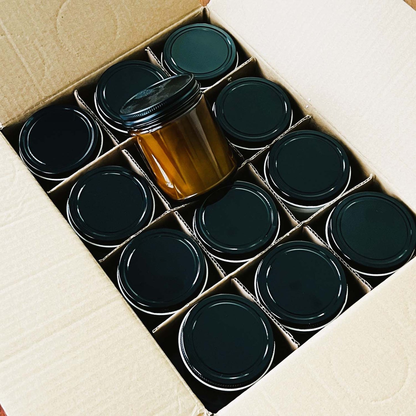 Box of 12 9oz amber jar candles with lids. Shows what you will order from Candle Builders with a wholesale candle order. 