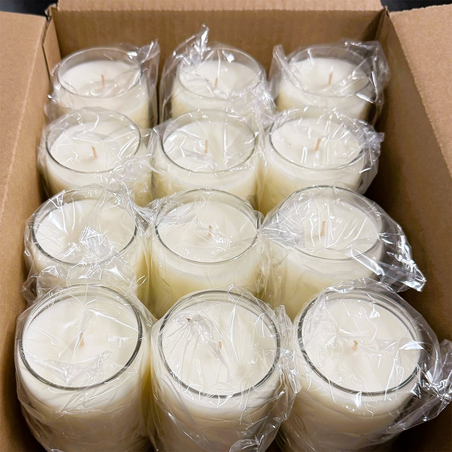 image showing a 12 pack of 13.75 oz blank candles in a shipping box. Each candle is wrapped in protective plastic. 