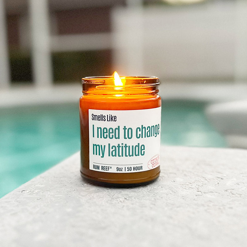 A beautiful 9oz Amber Jar Candle, lit, outside by a pool.  It is finished with private label branding for one of our clients.  