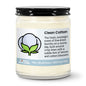 Candle jar labeled 'Clean Cotton' with a description of its scent on a white background